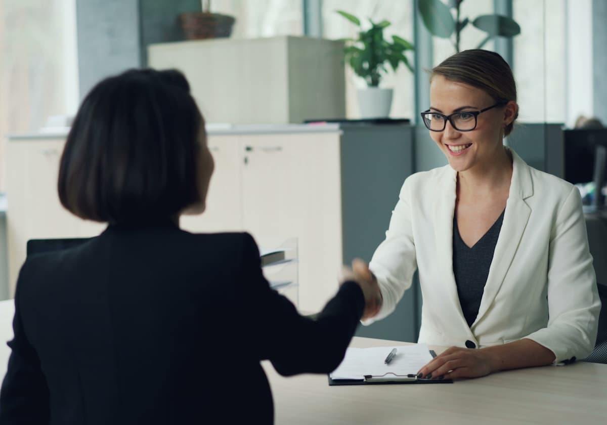 Two people shaking hands across a desk