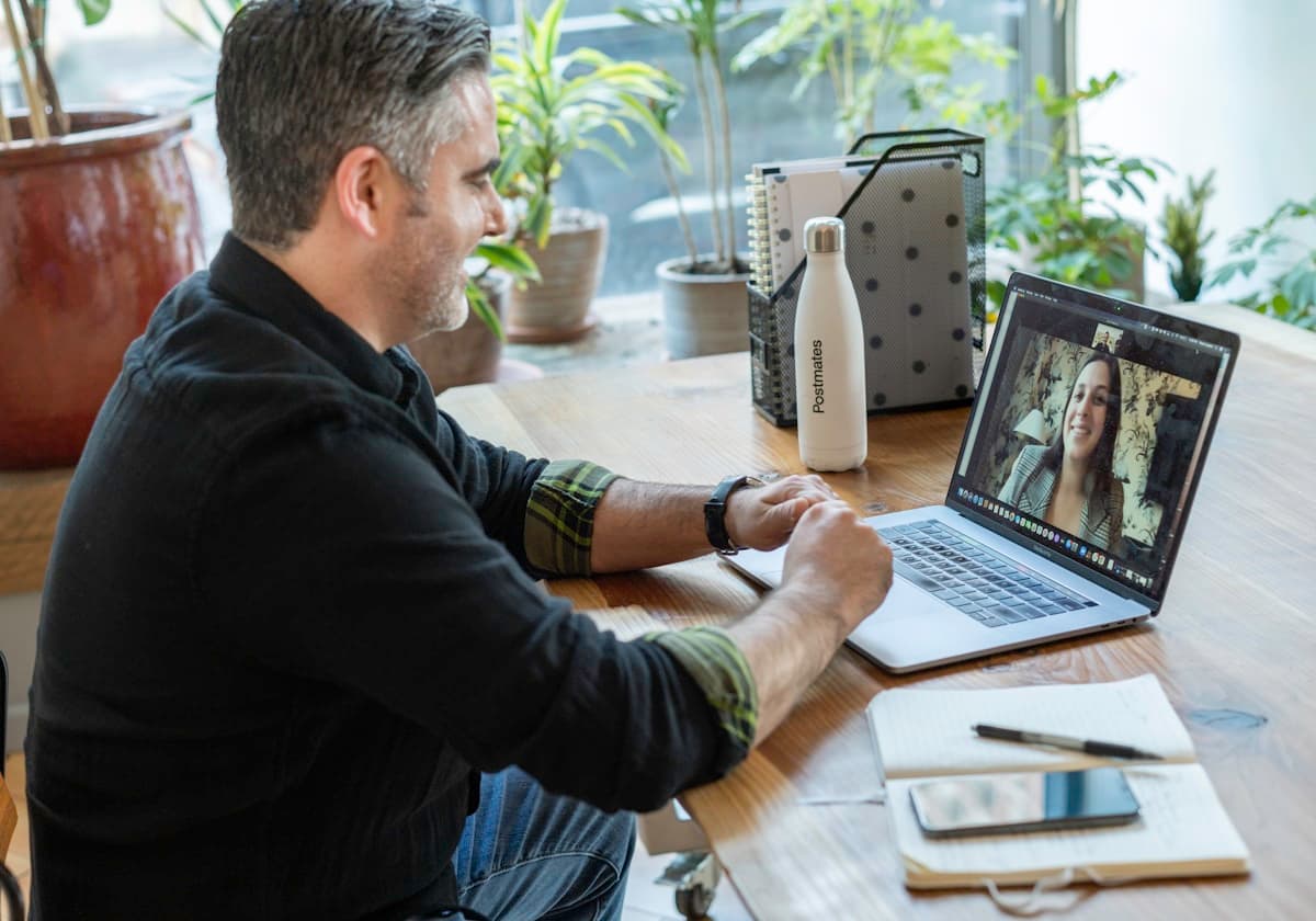 A person on a video call at a wooden desk